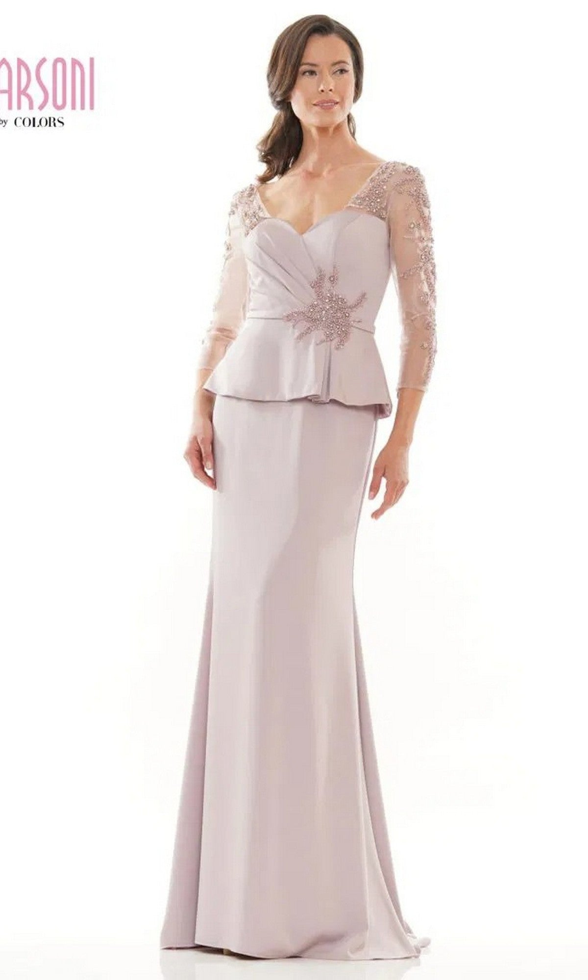 A woman stands against a plain background wearing the Marsoni MV1037 long formal dress in dusty rose, featuring sheer three-quarter sleeves and floral embellishments on the bodice.